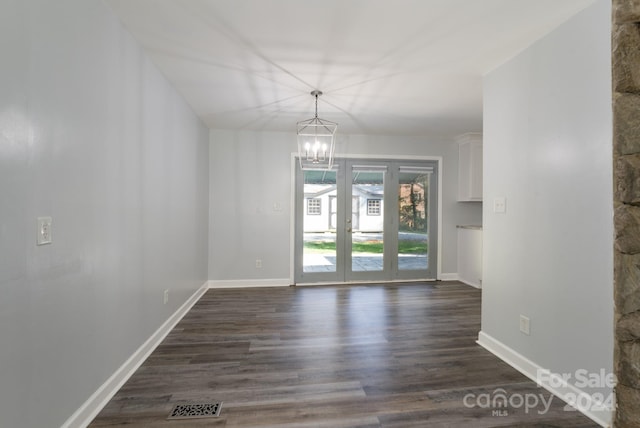 unfurnished room featuring dark wood-type flooring, a notable chandelier, and french doors