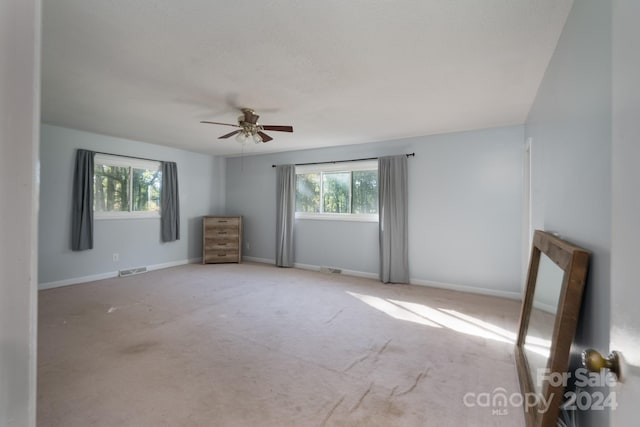 empty room featuring carpet, a healthy amount of sunlight, and ceiling fan