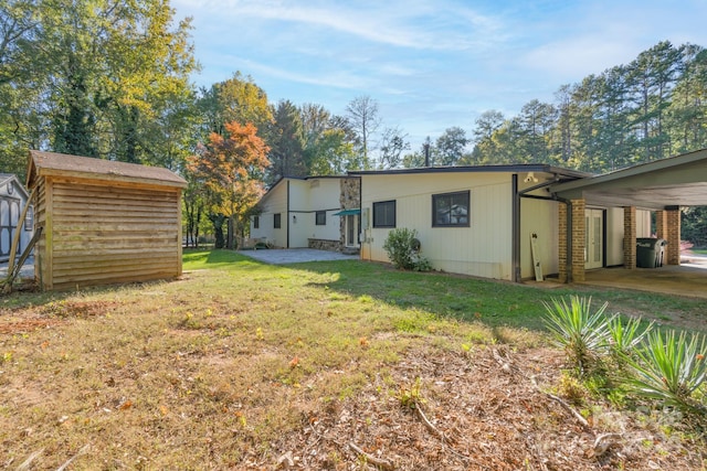 back of house with a yard, a patio, a shed, and a carport