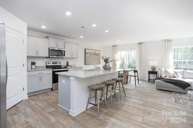 kitchen featuring a center island with sink, a breakfast bar, stainless steel appliances, and light hardwood / wood-style floors