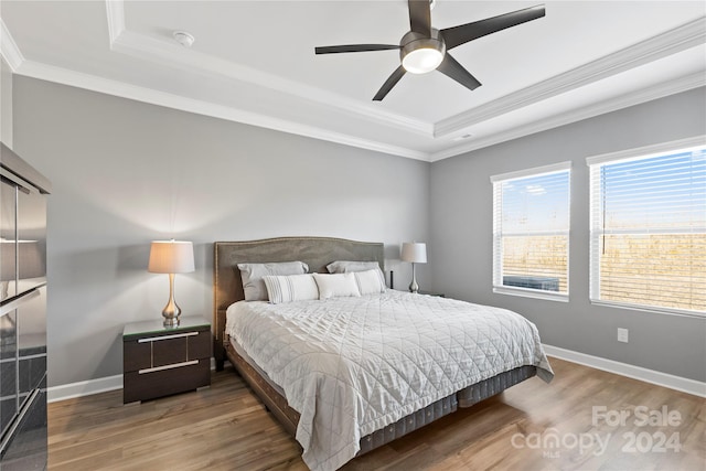 bedroom featuring crown molding, a raised ceiling, wood-type flooring, and ceiling fan