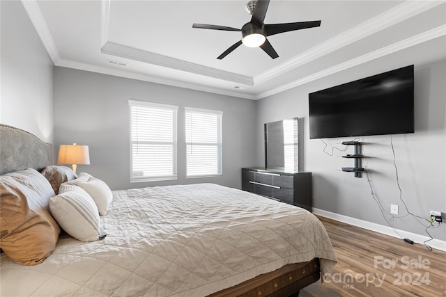 bedroom featuring ceiling fan, wood-type flooring, a tray ceiling, and ornamental molding