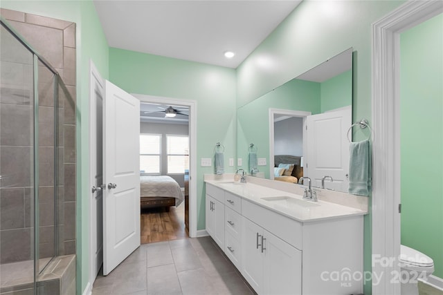 bathroom with toilet, a shower with shower door, vanity, and ceiling fan