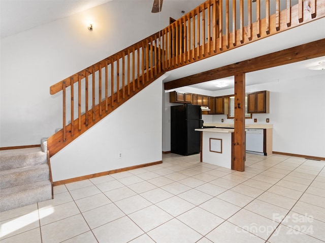 kitchen featuring light tile patterned floors, a towering ceiling, dishwasher, and black refrigerator