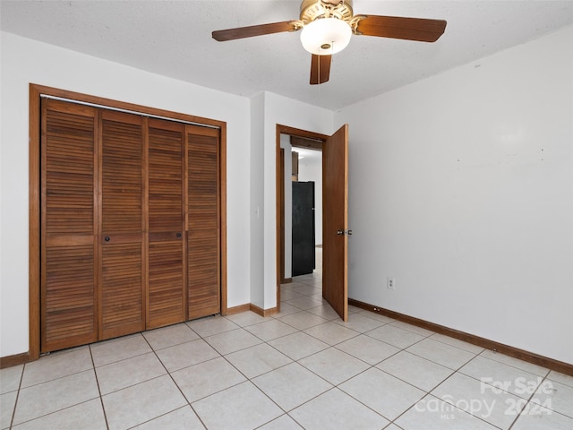 unfurnished bedroom featuring light tile patterned flooring, a textured ceiling, a closet, and ceiling fan