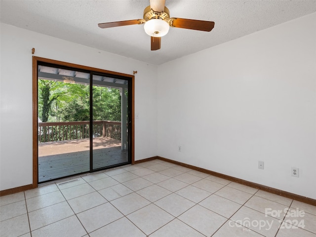 spare room featuring a textured ceiling, ceiling fan, and light tile patterned floors