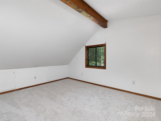 bonus room with a textured ceiling, lofted ceiling with beams, and light colored carpet