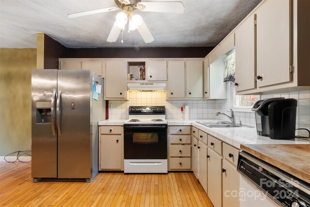 kitchen with tasteful backsplash, white cabinetry, sink, white appliances, and light hardwood / wood-style flooring