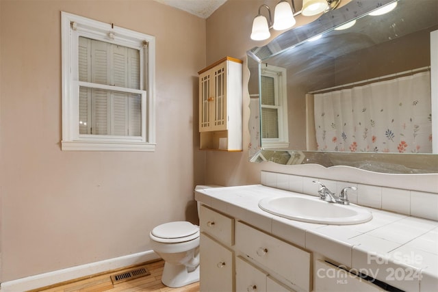 bathroom with toilet, vanity, and wood-type flooring