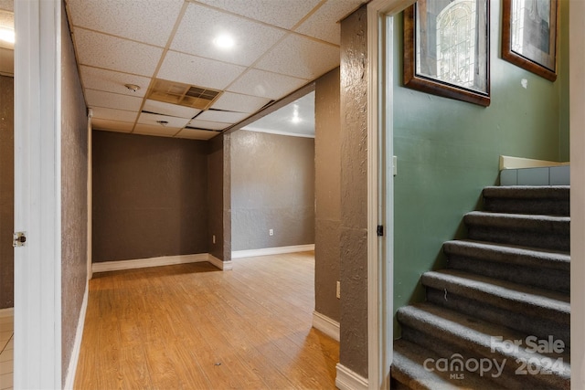 stairs with hardwood / wood-style flooring and a drop ceiling