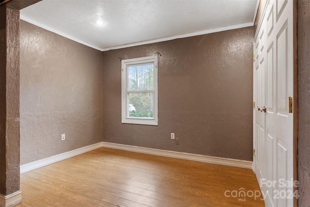 empty room with ornamental molding and light hardwood / wood-style floors