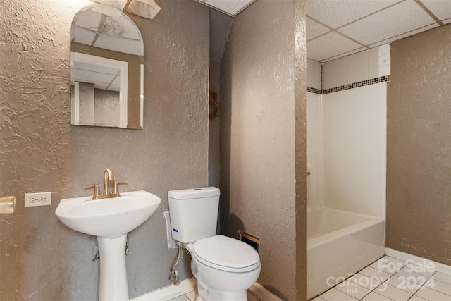 full bathroom with tile patterned flooring, a paneled ceiling, toilet, and bathing tub / shower combination