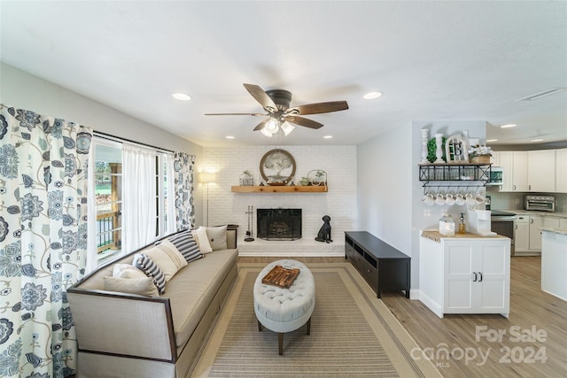 living room with ceiling fan, light wood-type flooring, and a fireplace