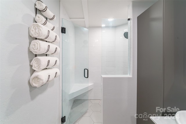 bathroom featuring toilet, a shower with shower door, and tile patterned flooring