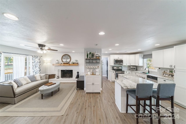 kitchen with white cabinetry, light hardwood / wood-style flooring, appliances with stainless steel finishes, and sink