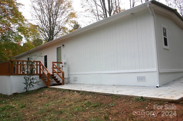 view of property exterior with a wooden deck and a patio area