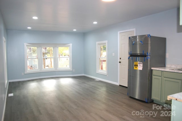 kitchen with green cabinetry, dark hardwood / wood-style floors, and stainless steel fridge