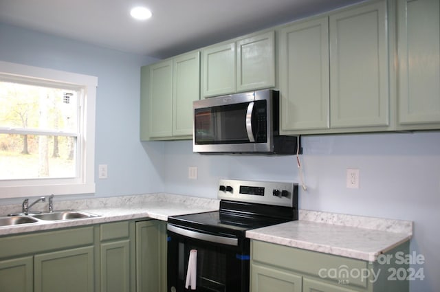 kitchen featuring stainless steel appliances, green cabinets, and sink