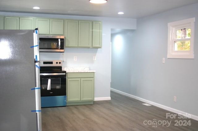 kitchen featuring dark hardwood / wood-style floors, stainless steel appliances, and green cabinets