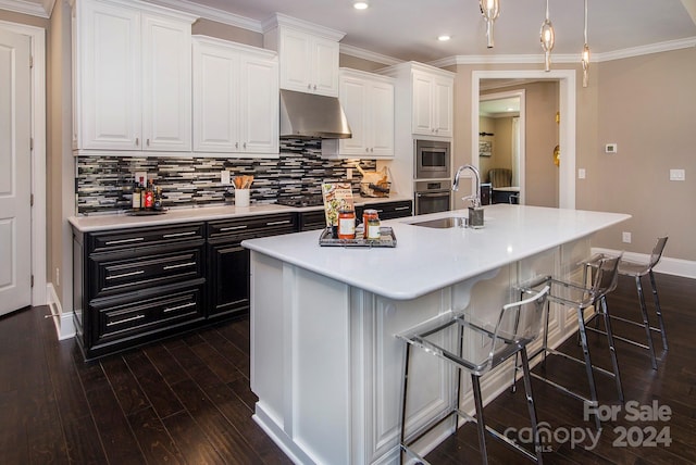 kitchen featuring sink, dark hardwood / wood-style flooring, white cabinets, a breakfast bar, and a kitchen island with sink