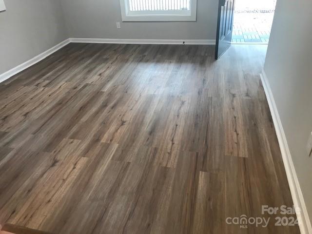 empty room featuring baseboards and dark wood-style floors