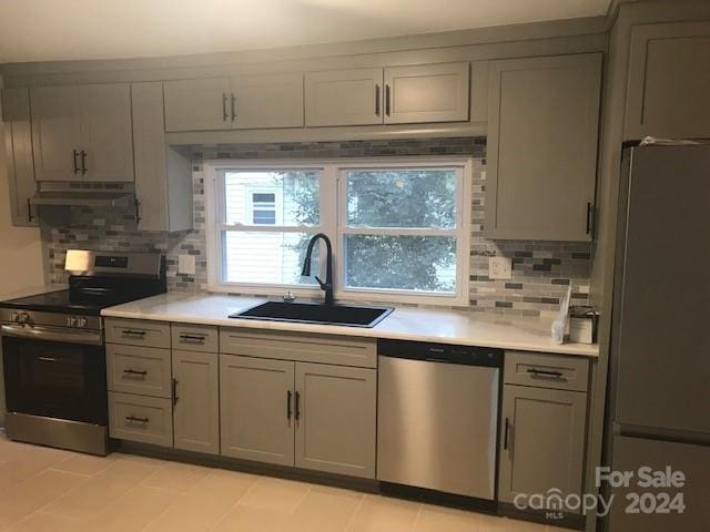 kitchen with stainless steel appliances, tasteful backsplash, gray cabinetry, and sink