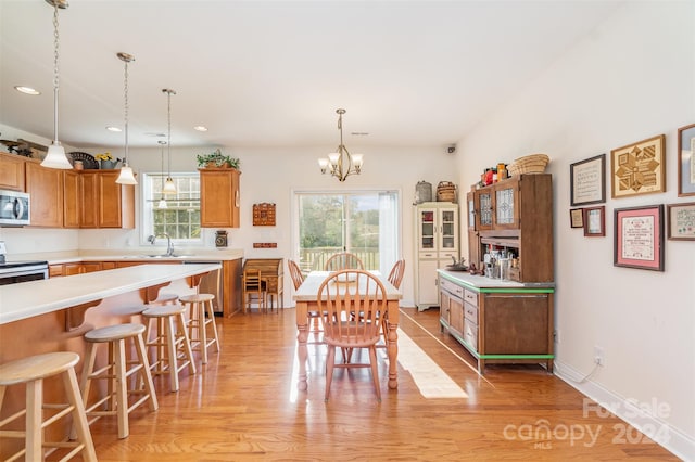 dining area featuring an inviting chandelier, sink, and light wood-type flooring