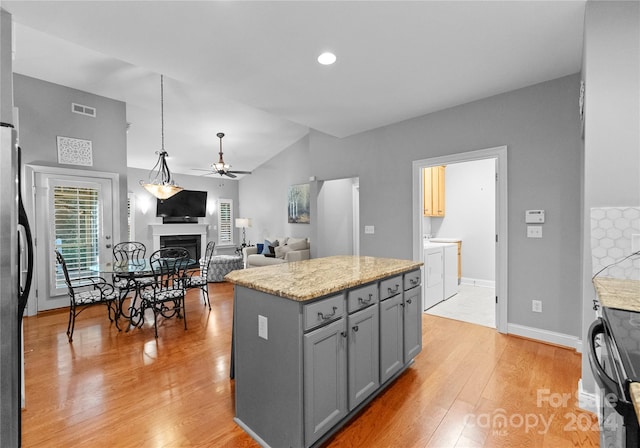 kitchen featuring appliances with stainless steel finishes, light hardwood / wood-style floors, gray cabinets, a kitchen island, and hanging light fixtures