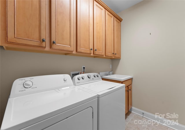 laundry area featuring washer and dryer, light tile patterned floors, and cabinets