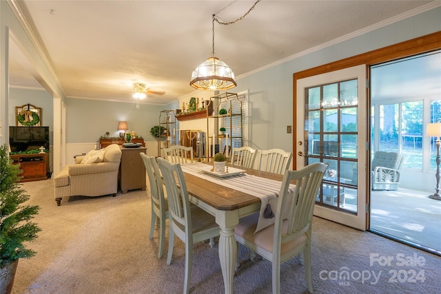 carpeted dining area with ceiling fan with notable chandelier and crown molding