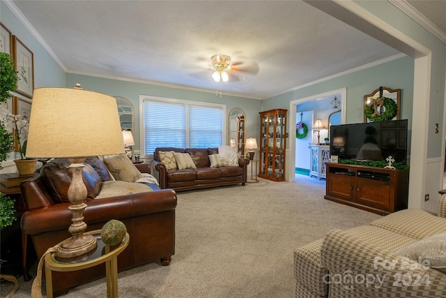 living room featuring a textured ceiling, light colored carpet, ceiling fan, and crown molding