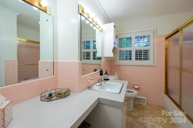 full bathroom with tile walls, tile patterned floors, ornamental molding, shower / bath combination with glass door, and toilet