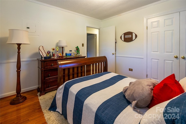 bedroom featuring dark wood-type flooring, a closet, a textured ceiling, and ornamental molding