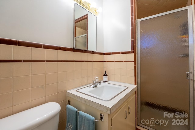 bathroom featuring tile walls, vanity, toilet, and a shower with door