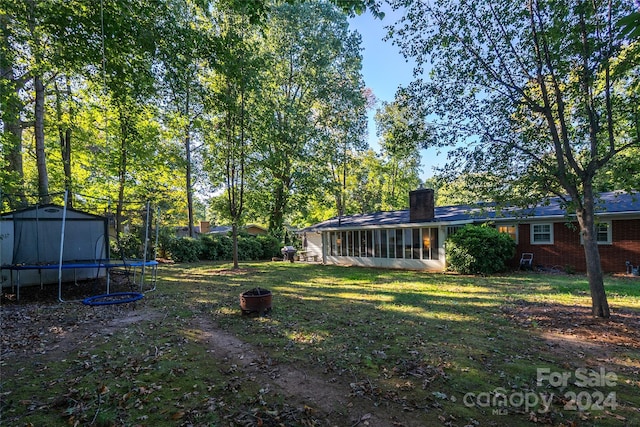 view of yard with a sunroom and a trampoline