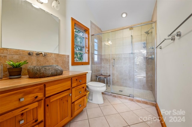 bathroom featuring backsplash, a shower with shower door, toilet, tile patterned floors, and vanity