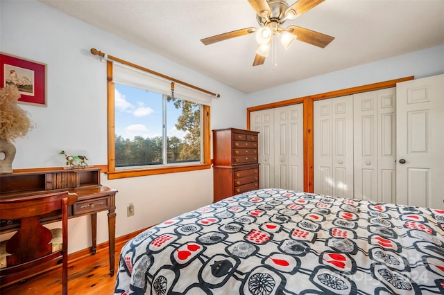 bedroom featuring ceiling fan, hardwood / wood-style flooring, and multiple closets