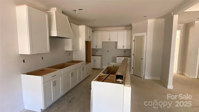 kitchen featuring white cabinetry, wall chimney range hood, baseboards, and black electric cooktop