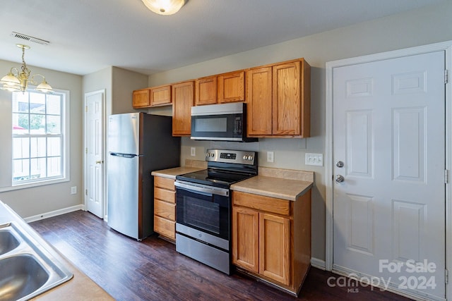 kitchen featuring sink, appliances with stainless steel finishes, hanging light fixtures, a chandelier, and dark hardwood / wood-style flooring