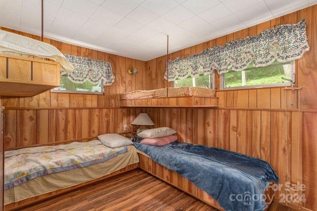 bedroom with wood-type flooring and wooden walls