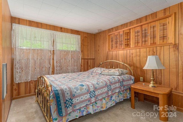 bedroom with wood walls and light colored carpet