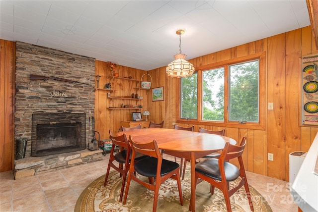 dining area with a stone fireplace and wooden walls