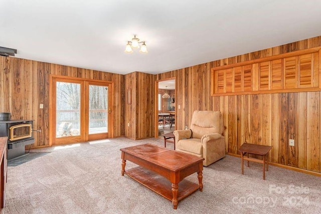 living room featuring a wood stove, wooden walls, and light carpet