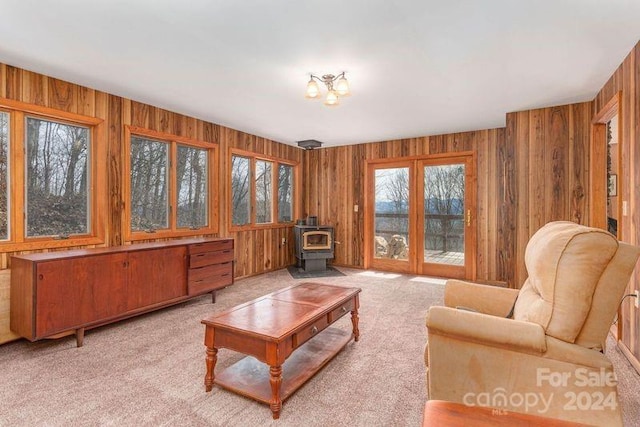 living room with wooden walls, a wood stove, and light carpet