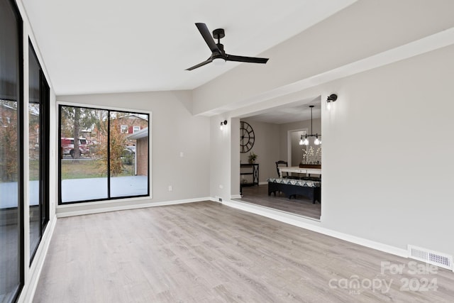 unfurnished room with lofted ceiling, hardwood / wood-style flooring, and ceiling fan with notable chandelier