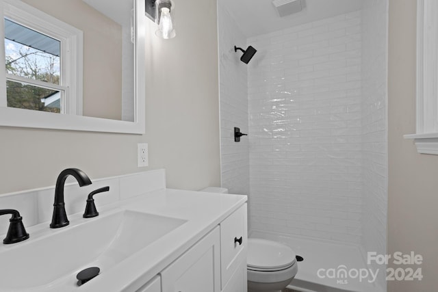 bathroom featuring a tile shower, toilet, and vanity