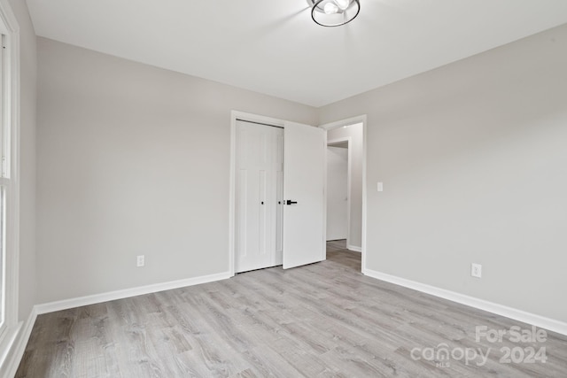 unfurnished bedroom with light hardwood / wood-style flooring and a closet