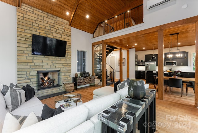 living room featuring a stone fireplace, high vaulted ceiling, wooden ceiling, an AC wall unit, and light hardwood / wood-style floors