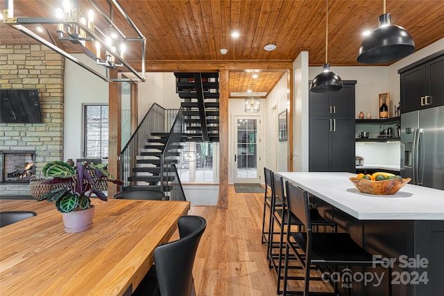 dining area featuring wood ceiling, light wood-type flooring, and a fireplace