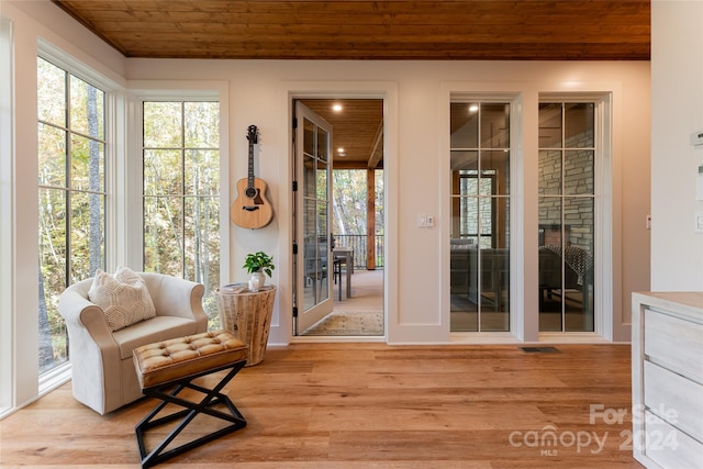 interior space with light hardwood / wood-style flooring, wooden ceiling, and a wealth of natural light